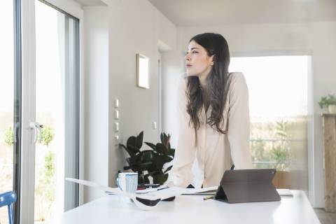 Young woman standing at table at home looking sideways model released Symbolfoto property released  UUF16951