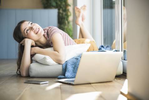Relaxed young woman lying at the window at home with laptop model released Symbolfoto property released  UUF16994
