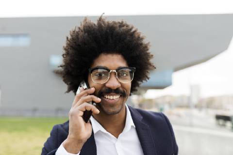 Spain, Barcelona, portrait of smiling businessman on cell phone in the city model released Symbolfoto  VABF02256