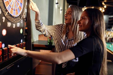 Two women playing darts setting electronic dartboard model released Symbolfoto property released  ZEDF02057