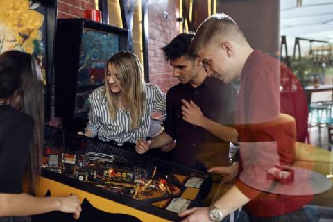 Man playing pinball watched by friends model released Symbolfoto property released  ZEDF02065