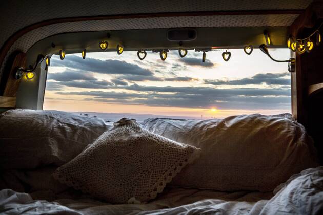 Camper van with cushion and fairy lights, view through rear window at sunset. Camper van with cushion and fairy lights, view through rear window at sunset.  57811