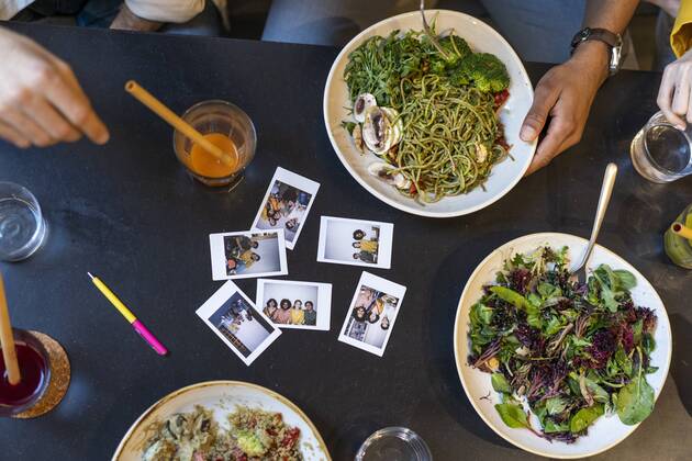 Group of friends having lunch in a restaurant with instant photos on table model released Symbolfoto property released  AFVF03484