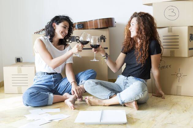 Two friends moving into new home clinking red wine glasses model released Symbolfoto property released  JPTF00224