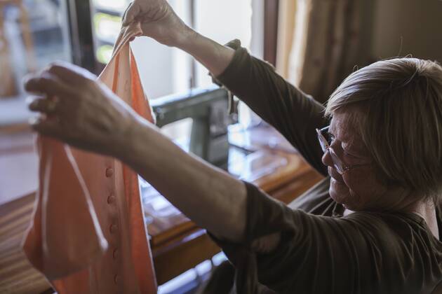 Senior woman holding a piece of clothing at home model released Symbolfoto property released  LJF00116