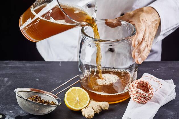  Man pouring kombucha SCOBY tea into jar  Copyright: xfoodandmorex Panthermedia25786853