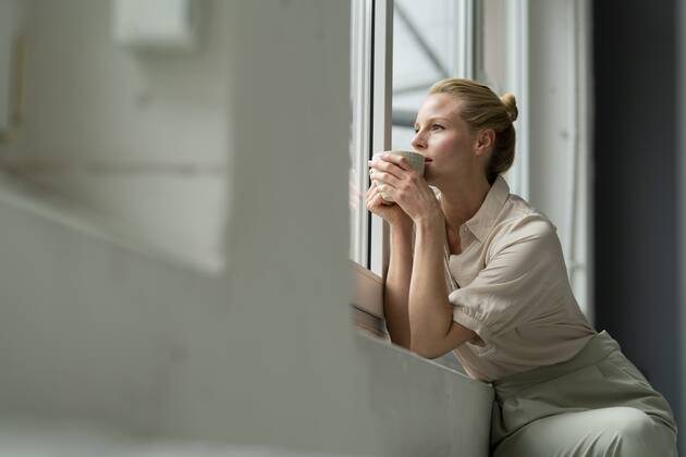 Young businesswoman with cup of coffee looking out of window model released Symbolfoto property released  JOSF03532