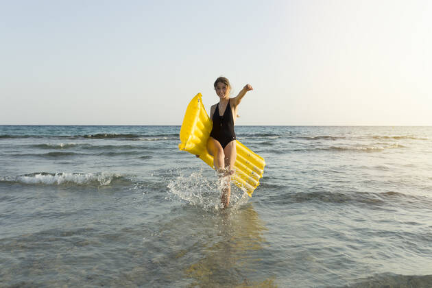 Young woman with yellow airbed at the beach model released Symbolfoto JPTF00268
