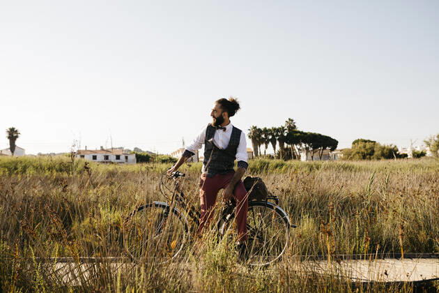 Well dressed man with his bike on a wooden walkway in the countryside having a break model released Symbolfoto  JRFF03583