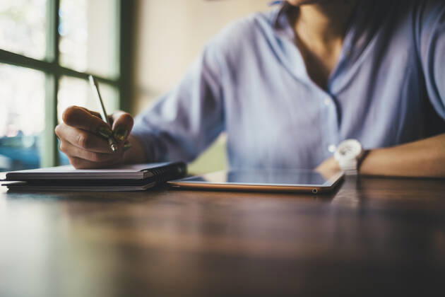 Woman sitting in a cafe using a digital tablet and taking notes model released Symbolfoto OYF00051