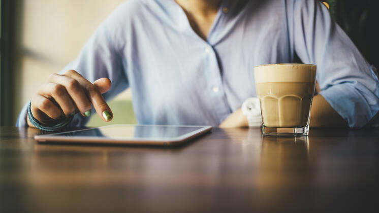Woman sitting in a cafe using a digital tablet and drinking a coffee model released Symbolfoto OYF00053