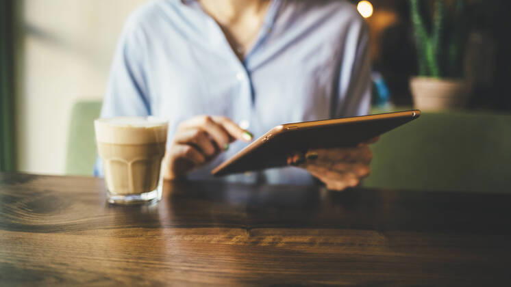 Woman sitting in a cafe using a digital tablet and drinking a coffee model released Symbolfoto OYF00055