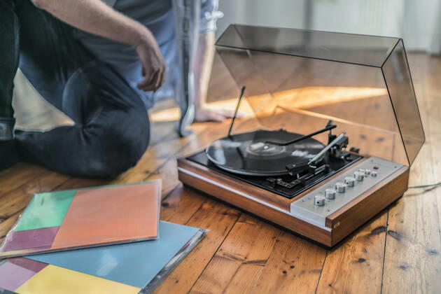 Close-up of man sitting on the floor at home with a record player model released Symbolfoto property released  RIBF01028