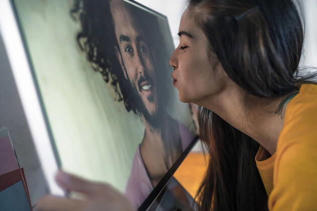 Young woman kissing man on computer screen model released Symbolfoto property released  RIBF01053