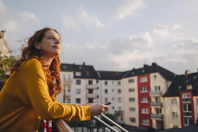 Redheaded woman standing on roof terrace model released Symbolfoto property released  KNSF06618