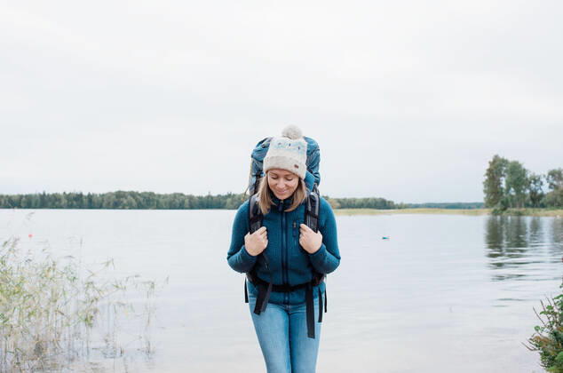 woman smiling backpacking by the beach Sweden, Stockholm County, Norrtälje CR_RABE191022-210187-01