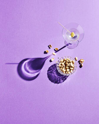 Directly above shot of pistachios and martini glass with shadow on purple background  KSWF02073
