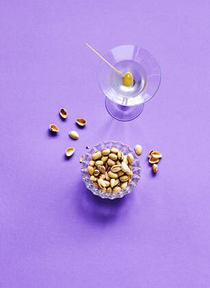 Directly above shot of pistachios and martini glass on purple background  KSWF02074