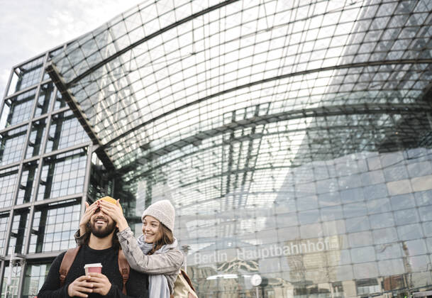 Happy young woman surprising boyfriend at the central station, Berlin, Germany model released Symbolfoto  AHSF01483
