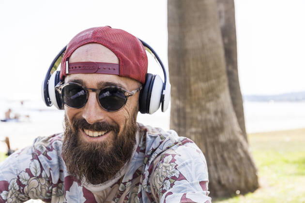 Mature man with red basecap, sunglasses and white headphones model released Symbolfoto TCF06231