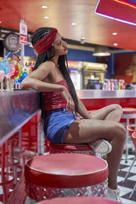Young woman with braided hairstyle sitting on a bar on red stool model released Symbolfoto property released  VEGF01159