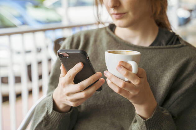 Close-up of young woman using cell phone and holding coffee cup model released Symbolfoto  AFVF04839