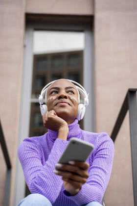 Portrait of white haired woman with white headphones and stickers in her face listening to music and laughing model released Symbolfoto  AFVF05022