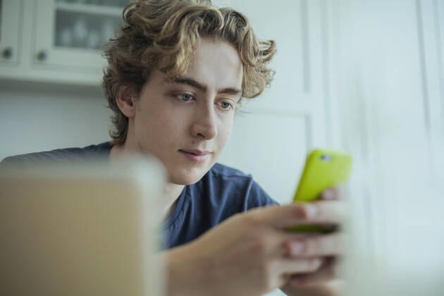 Young man using smartphone at home model released Symbolfoto property released  AJOF00081