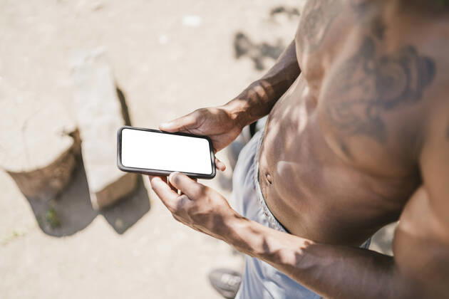 Young man during workout, holding smartphone model released Symbolfoto  FBAF01214