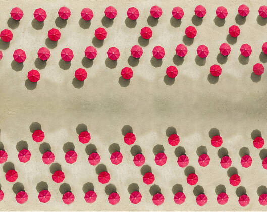 Aerial view of arrangement of red beach umbrellas on sandy beach  KNTF04088