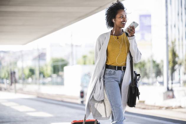 Smiling young woman on the go using smartphone at the train station model released Symbolfoto  UUF20166