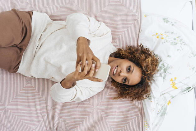 Young woman lying in bed using smartphone model released Symbolfoto property released  VPIF01921