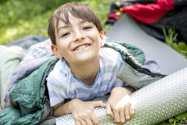 Little boy lying on sleeping bag, looking at camera model released Symbolfoto  WESTF24489