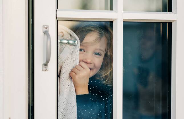 IMAGO Creative, Jahreszeit Sommer, Sommerferien young girl looking through a door window smiling looking happy Stockholm, Stockholm County, Sweden CR_RABE191212-252792-01