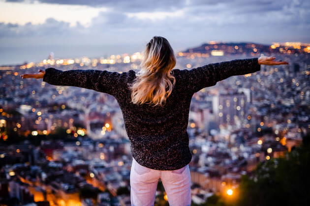 Young woman sitting on railing above the city using cell phone, Barcelona, Spain model released Symbolfoto GIOF07947