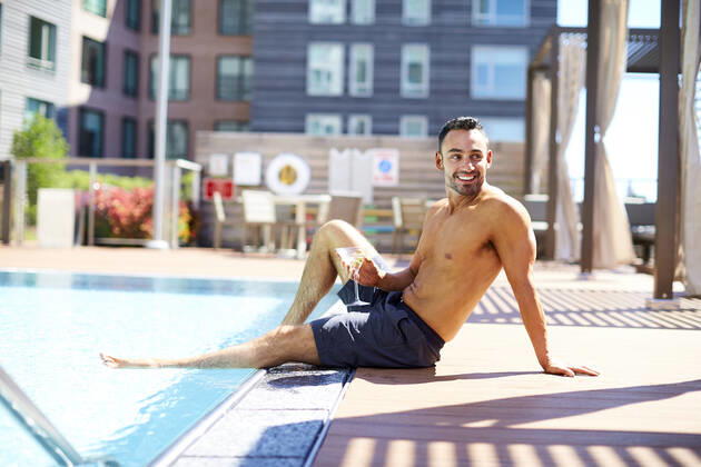 A man relaxes with a drink by the pool. Boston, MA, United States ,model released, Symbolfoto CR_SDXQ200115-197157-01