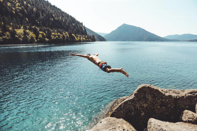 IMAGO Creative: Ende des Sommers Side view of young male jumping in alpine lake in front of mountains Port Angeles, WA, United States ,model released, Symbolfoto CR_MAKO200206D-304979-01