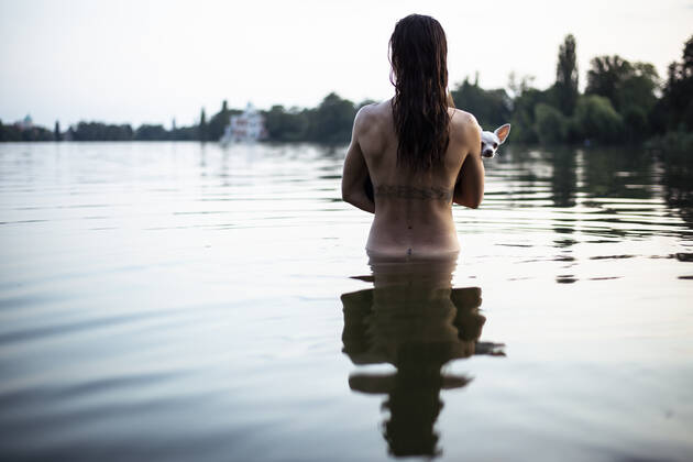 back view of strong woman holding small dog in natural berlin lake ,model released, Symbolfoto CR_PIDODS200220B-239379-01