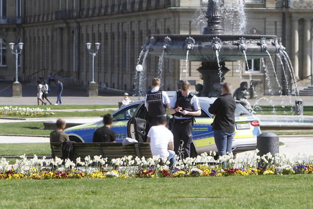 A police patrol of the Baden Württemberg state police checks the personal data of passers-by who were sitting on a bench on the Schlossplatz and thus had not kept the prescribed minimum distance in the city centre of Stuttgart, Baden Württemberg, Bavaria, Germany