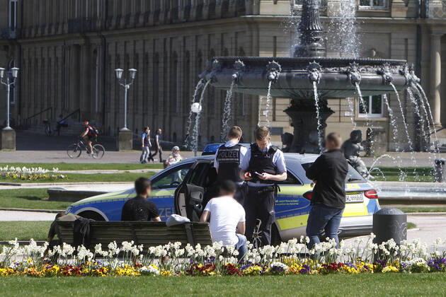 A police patrol of the Baden Württemberg state police checks the personal data of passers-by who were sitting on a bench on the Schlossplatz in a threesome and thus had not kept the prescribed minimum distance in the city centre of Stuttgart, Baden Württemberg, Bavaria, Germany