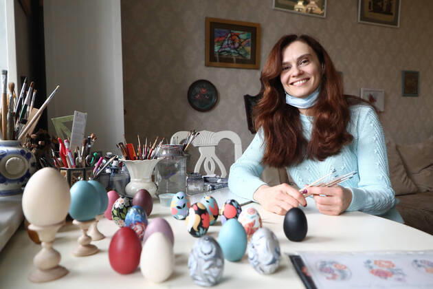 MOSCOW, RUSSIA - APRIL 16, 2020: Artist Iya Tokareva paints wooden Easter eggs Gorodets-style at her home studio; Gorodets painting, one of the traditional Russians handicrafts, originated in the middle of XIX century in the town of Gorodets, the Nizhny Novgorod Region. Anton Novoderezhkin TASS  TS0D5FDB