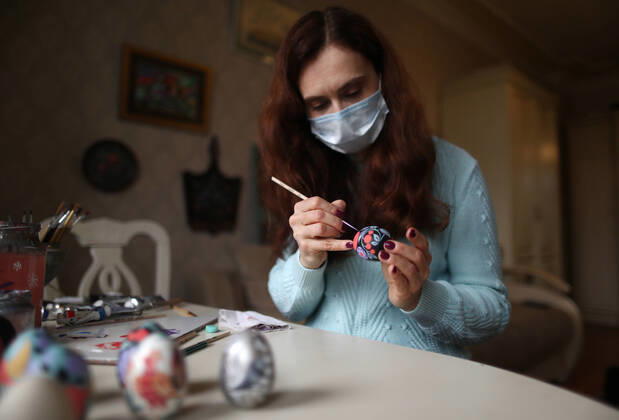 MOSCOW, RUSSIA - APRIL 16, 2020: Artist Iya Tokareva paints a wooden Easter egg Gorodets-style at her home studio; Gorodets painting, one of the traditional Russians handicrafts, originated in the middle of XIX century in the town of Gorodets, the Nizhny Novgorod Region. Anton Novoderezhkin TASS  TS0D5FE1