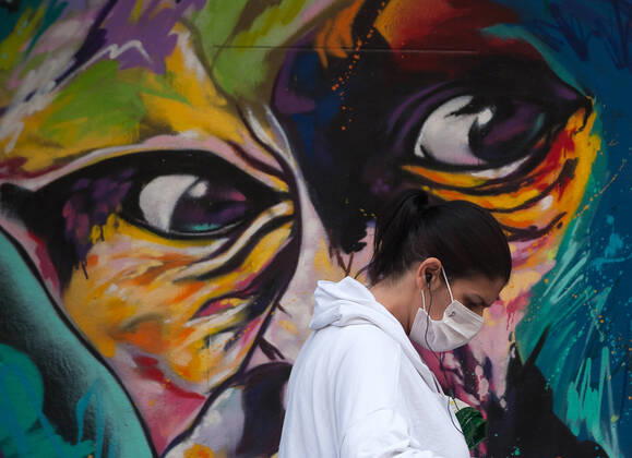 April 16, 2020, Malaga, Spain: A woman wearing a face mask as a preventive measure, walking past a mural during the covid-19 crisis..Following the confinement decreed by the Spanish government and will extended until 10th May, people are confinement in their homes causing an exceptional situation of unusual urban scenes such as empty streets. Malaga Spain - ZUMAs197 20200416_zaa_s197_059 Copyright: xJesusxMeridax