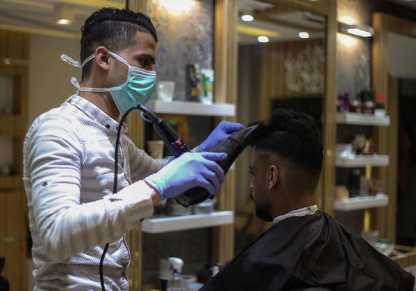 Daily Life at Barber in Southern Gaza Strip, Palestine amid Coronavirus Outbreak - 16 April 2020. A Palestinian barber wearing a face mask and a medical glove with his hand as a precautionary measure against Coronavirus (COVID-19), sterilizes his tools before cutting the customer s hair in Khan Yunis, southern Gaza Strip, Palestine, April 16, 2020. (Photo by Yousef Masoud INA Photo Agency imago images) 