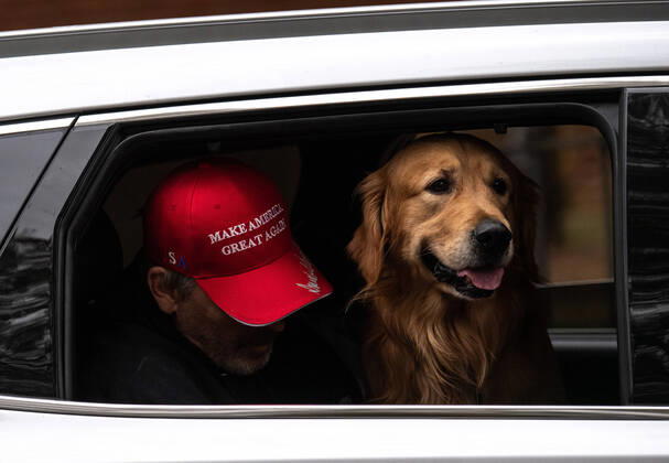 A man wears a Trump hat as he sits next to his dog during a vehicle during a protest to reopen Maryland and end the stay at home order imposed during the Coronavirus COVID-19 pandemic, near the state capitol building in Annapolis, Maryland on Saturday, April 18, 2020. Drivers circled Annapolis hoking their horns and calling for Gov. Larry Hogan (R-MD) to end the stay at home order.  WAP20200418322 KEVINxDIETSCH