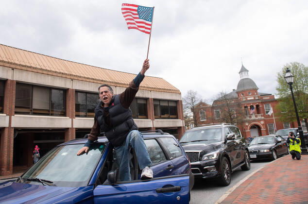 A man yells from the door of his vehicle during a car protest to reopen Maryland and end the stay at home order imposed during the Coronavirus COVID-19 pandemic, near the state capitol building in Annapolis, Maryland on Saturday, April 18, 2020. Drivers circled Annapolis hoking their horns and calling for Gov. Larry Hogan (R-MD) to end the stay at home order.  WAP20200418332 KEVINxDIETSCH