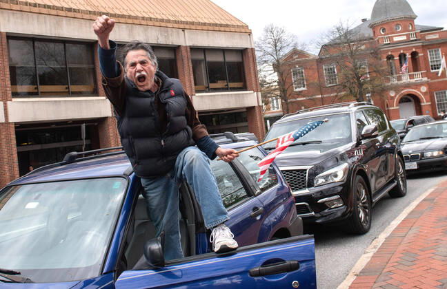 A man yells from the door of his vehicle during a car protest to reopen Maryland and end the stay at home order imposed during the Coronavirus COVID-19 pandemic, near the state capitol building in Annapolis, Maryland on Saturday, April 18, 2020. Drivers circled Annapolis hoking their horns and calling for Gov. Larry Hogan (R-MD) to end the stay at home order.  WAP20200418342 KEVINxDIETSCH