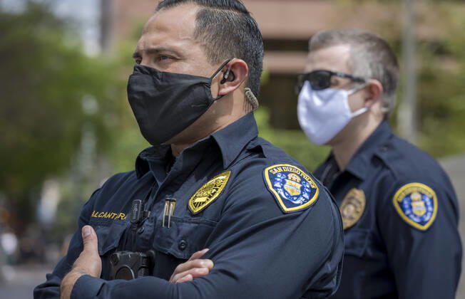 April 18, 2020, San Diego, California, US: San Diego police watch from across the street as protesters at a Liberate San Diego rally in downtown San Diego on Saturday waved signs and held banners complaining that they wanted the state to lift its stay at home order, a measure meant to reduce the spread of the coronavirus. The event was clearly political, with an overwhelming amount of signs and banners supporting President Trump. San Diego US - ZUMAp23_ 20200418_zaf_p23_020 Copyright: xDavidxPollerx