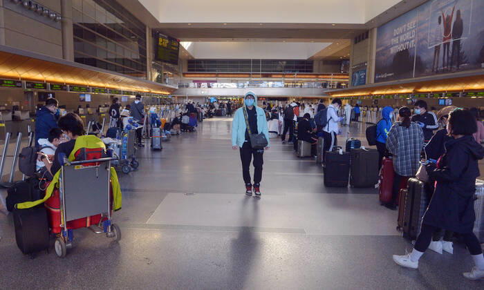 Hundreds of passengers form a line to check-in and board a China Southern Airlines midnight flight to China on Sunday, April 19, 2020 in Los Angeles. Passengers at the front of the line arrived at 5:30 a.m., with many others standing in line since 8 a.m. to ensure they would have a seat before the plane was full. Mayor Eric Garcetti said 95% of air travel has stopped in his city as Los Angeles sees the biggest drop of airplane travel in LAX history.  LAP2020041916 JIMxRUYMEN