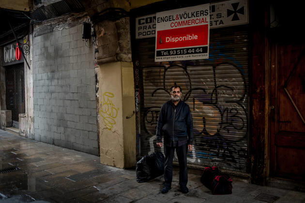 April 20, 2020, Barcelona, Catalonia, Spain: In Barcelona downtown a homeless man natural from India takes shelter form the rain under a porch close to a real estate company banner offering a renting place. Daily coronavirus deaths in Spain fall to 399, while confirmed cases now exceed 200,000. Barcelona Spain - ZUMAb137 20200420_zap_b137_013 Copyright: xJordixBoixareux